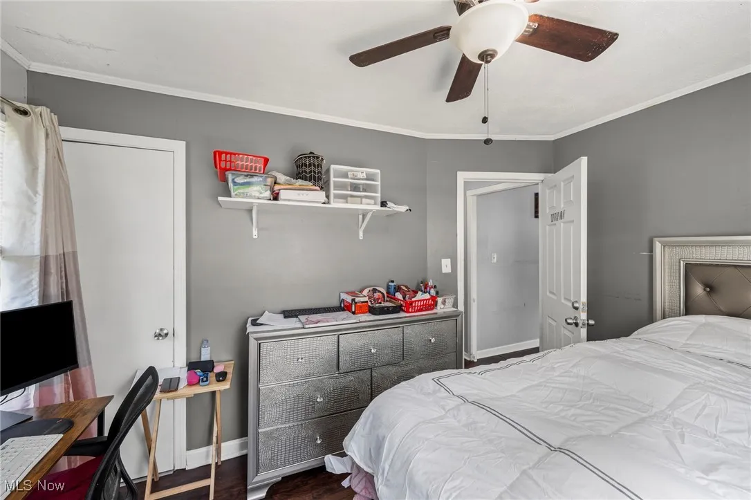 Bedroom featuring ornamental molding, wood finished floors, and a ceiling fan