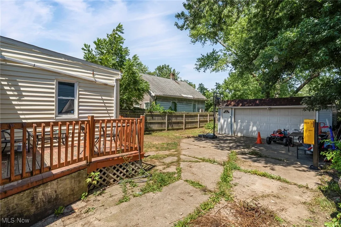View of yard with a detached garage, an outdoor structure, and a wooden deck