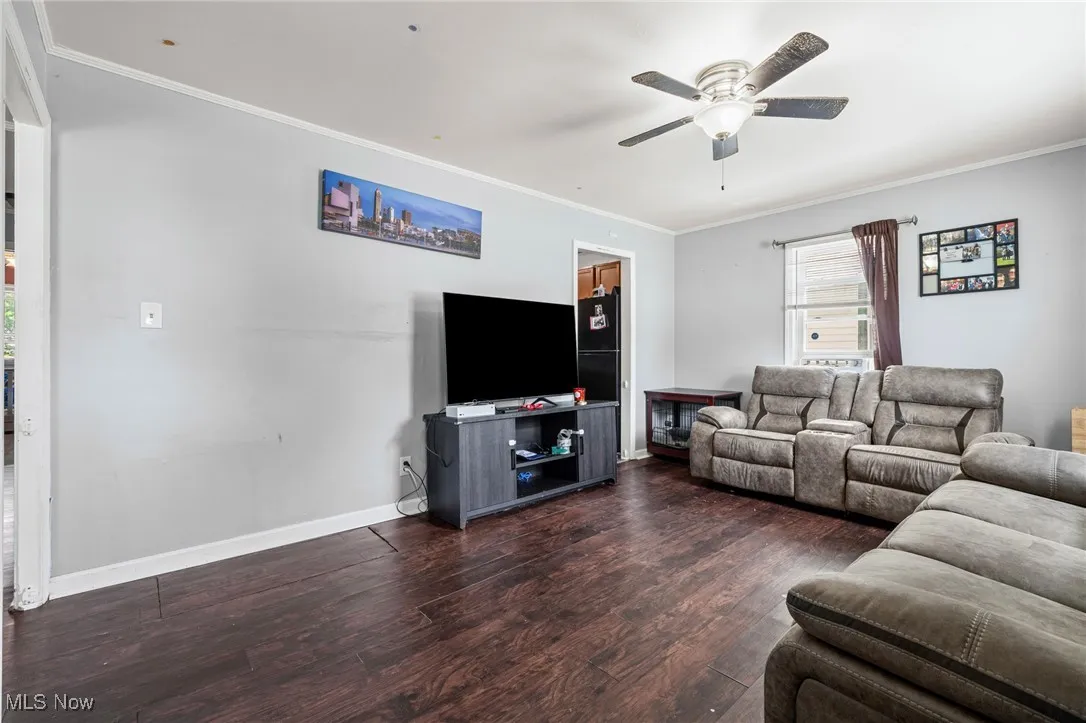Living room with ornamental molding, ceiling fan, and wood finished floors