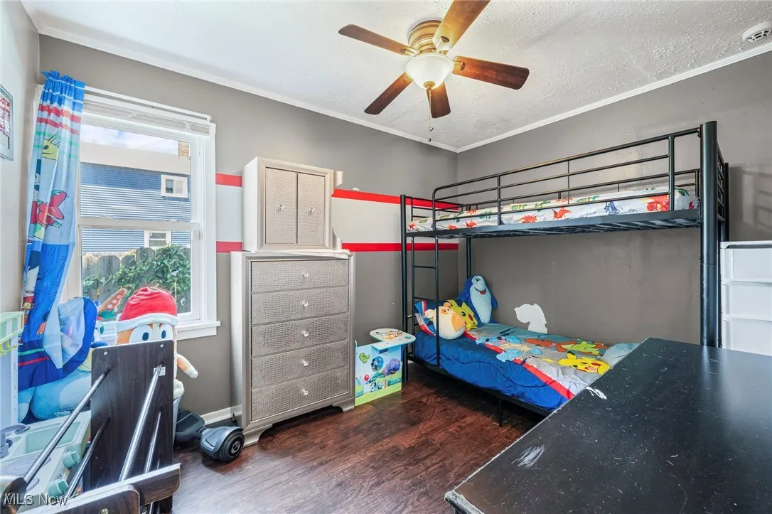 Bedroom featuring wood finished floors, ornamental molding, a textured ceiling, and a ceiling fan
