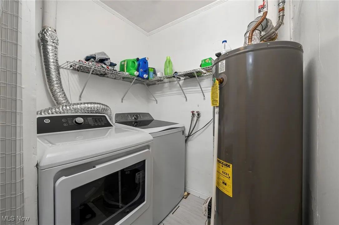 Washroom featuring washing machine and clothes dryer, electric water heater, and crown molding