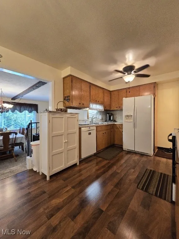 Kitchen with white appliances, dark wood-type flooring, a textured ceiling, brown cabinetry, and a ceiling fan