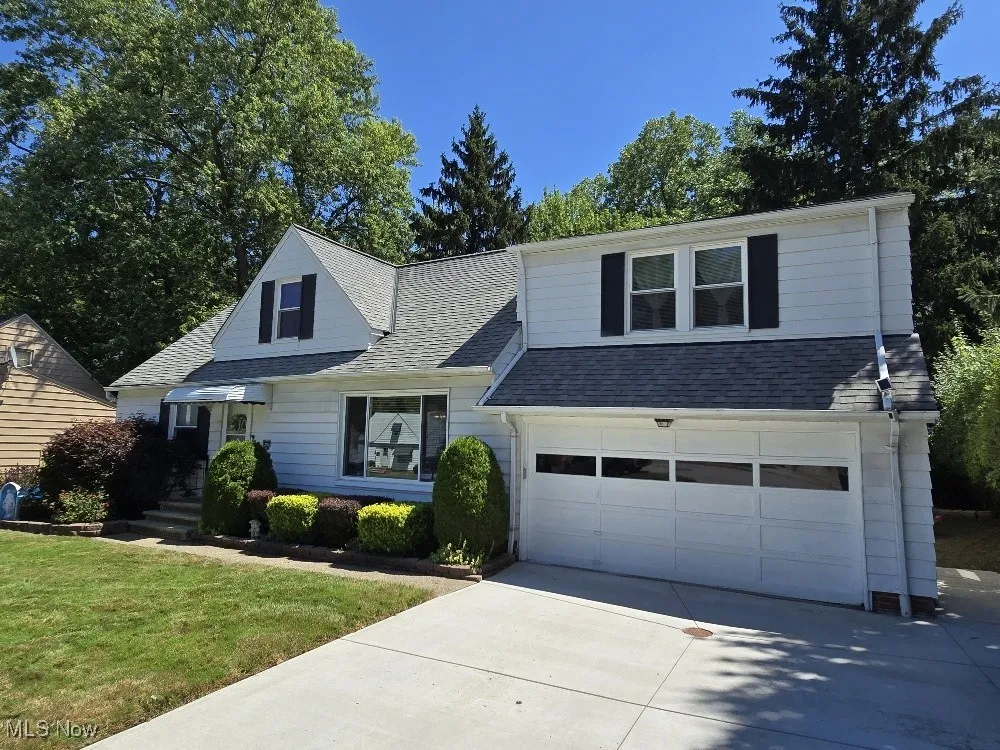 View of front of home with roof with shingles, driveway, and a front lawn