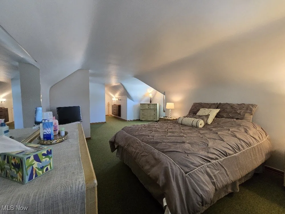 Bedroom with carpet floors and vaulted ceiling
