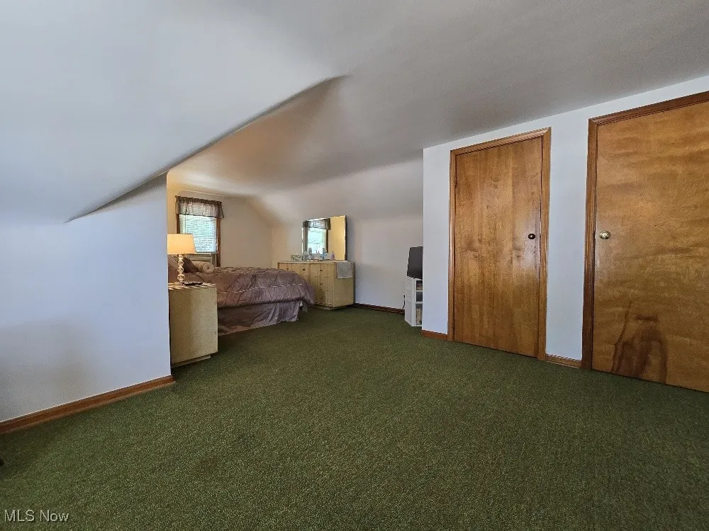 Unfurnished bedroom featuring carpet floors and vaulted ceiling
