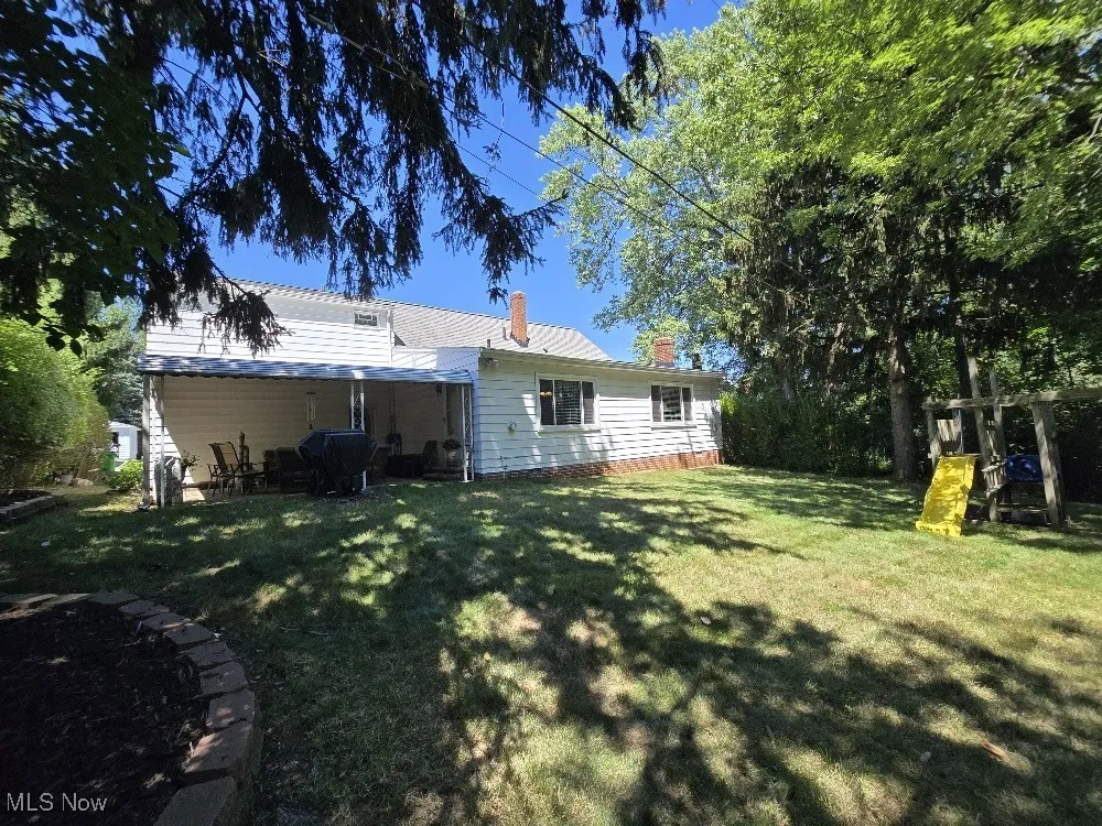 Rear view of house featuring a chimney, a yard, and a patio area
