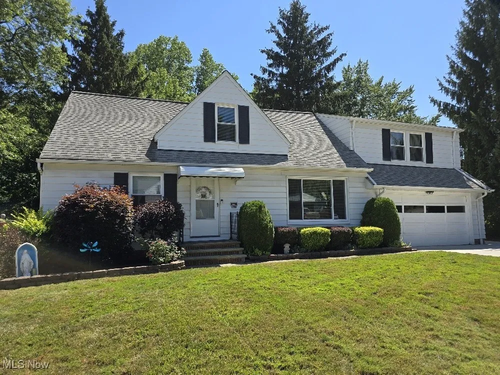 View of front of home featuring a front yard, a shingled roof, a garage, and concrete driveway