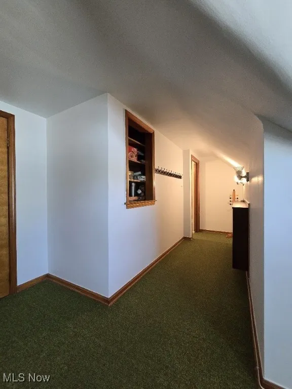 Hall featuring dark carpet and a textured ceiling