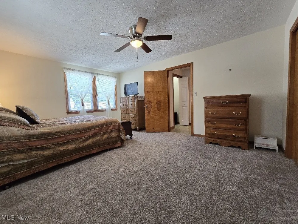 Carpeted bedroom featuring a textured ceiling and ceiling fan