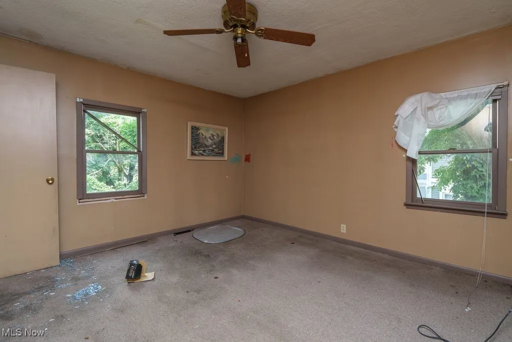 Empty room with a textured ceiling and ceiling fan