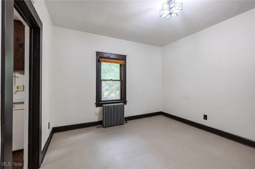 Empty room featuring radiator and baseboards