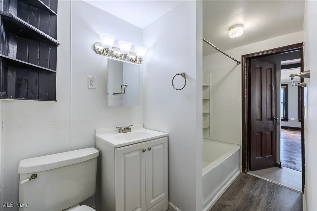 Bathroom featuring wood finished floors, vanity, and tub / shower combination