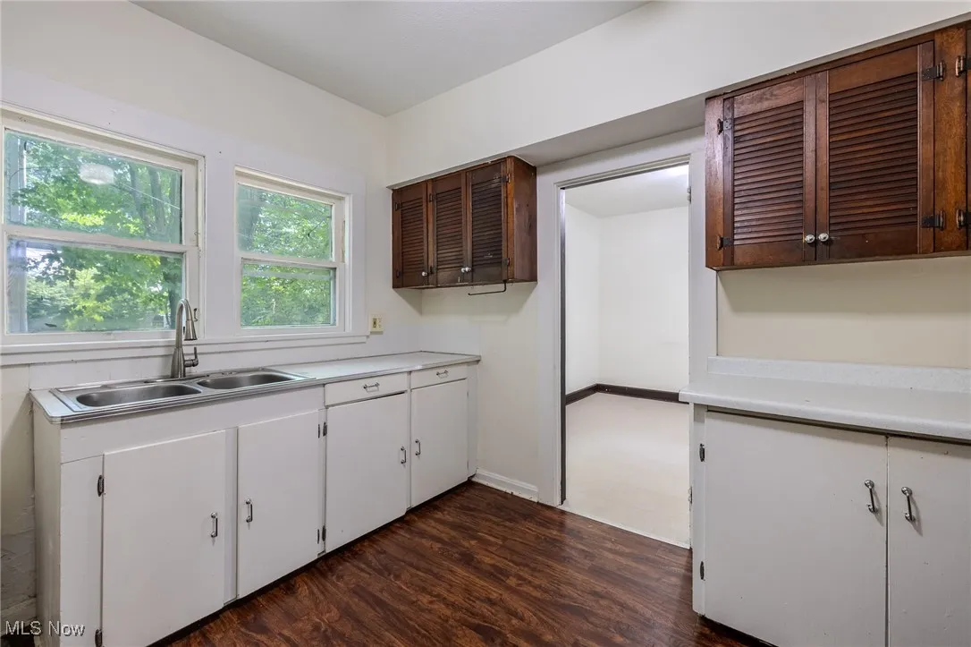 Kitchen with light countertops, dark wood finished floors, and white cabinets