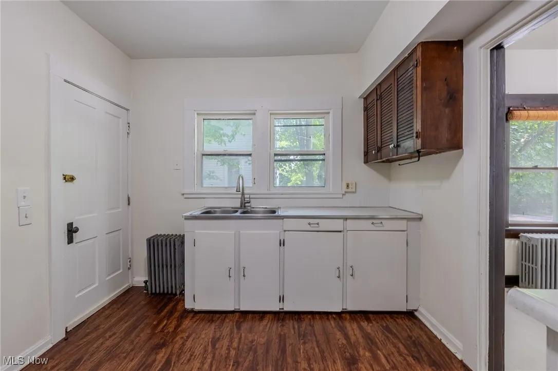 Kitchen with light countertops, dark wood-type flooring, and radiator