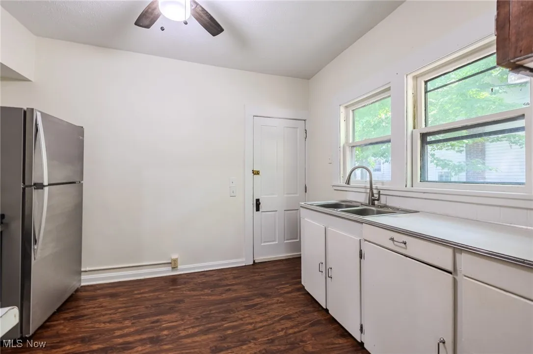 Kitchen featuring freestanding refrigerator, dark wood-type flooring, a ceiling fan, light countertops, and white cabinets