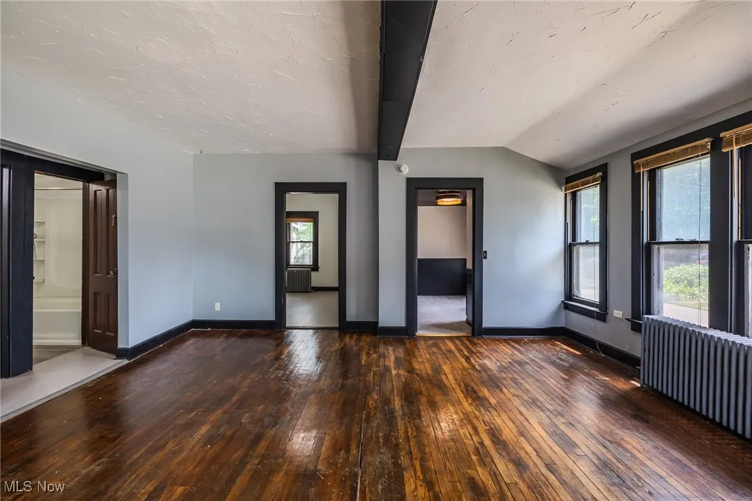 Empty room with hardwood / wood-style floors, radiator heating unit, and a textured ceiling
