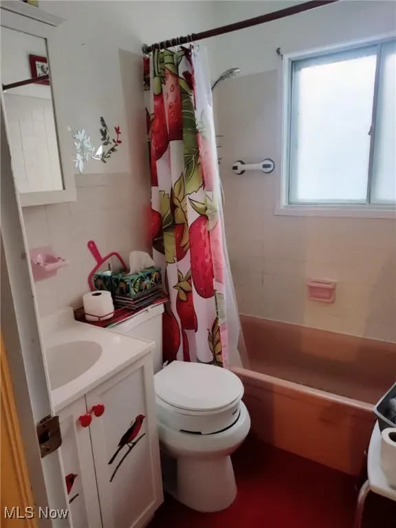 Bathroom featuring vanity, shower / tub combo with curtain, and tile walls