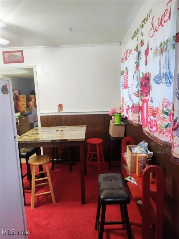 Dining area with wainscoting, carpet, and wood walls