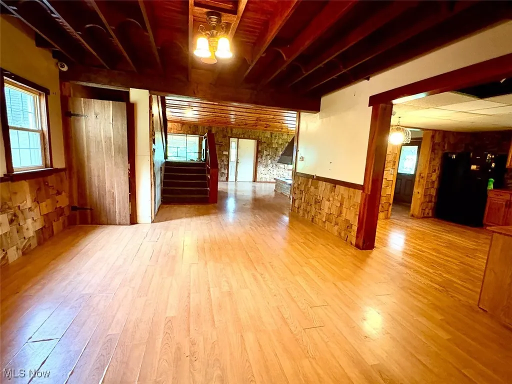 Dining room featuring wainscoting, wood finished floors, stairs, and wooden walls