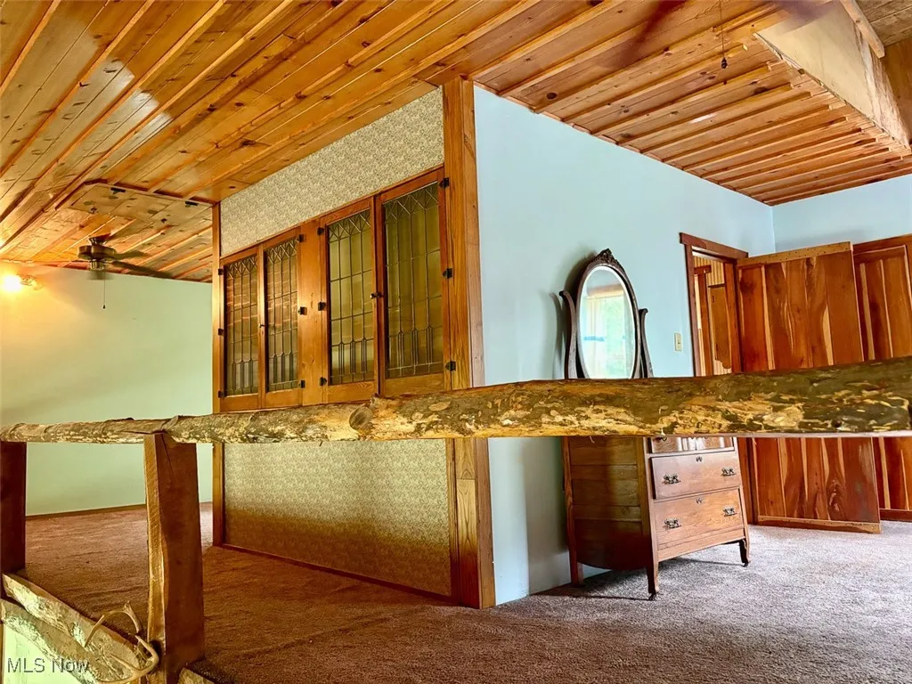 Loft featuring wooden ceiling, carpet floors, glass insert cabinets, and brown cabinetry