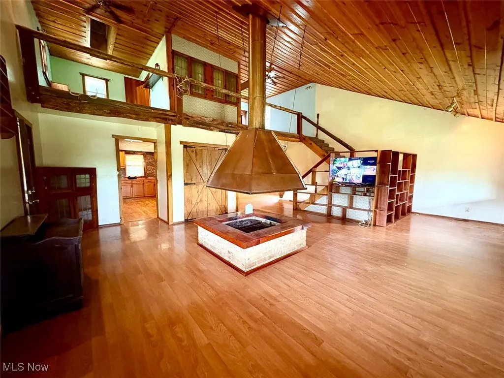 Living room featuring wood ceiling, high vaulted ceiling, wood finished floors, and stairway