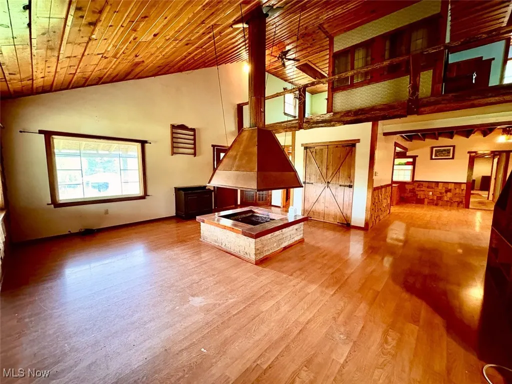 Unfurnished living room with high vaulted ceiling, wood ceiling, and wood finished floors