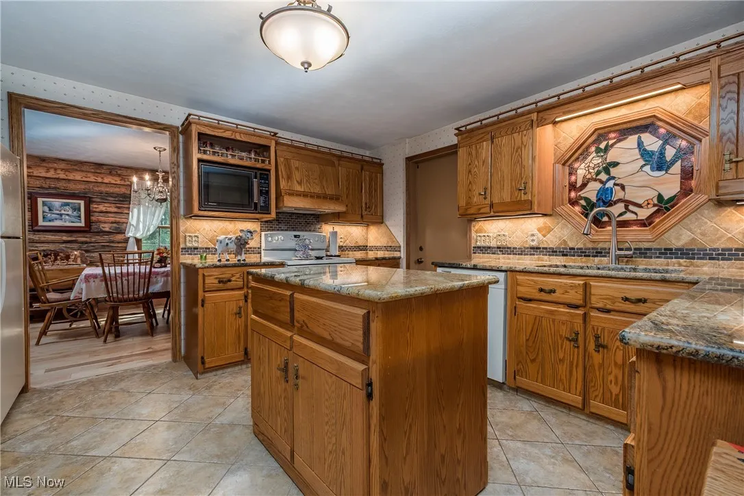 Kitchen with a sink, black microwave, electric range oven, a kitchen island, and premium range hood