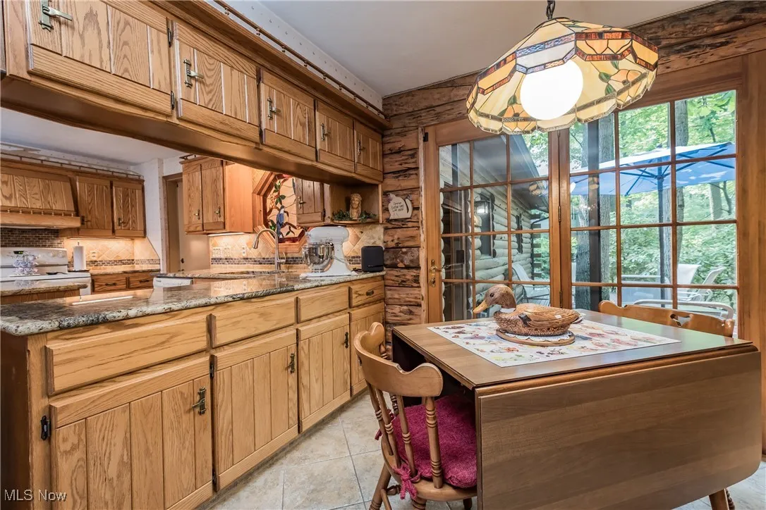 Kitchen featuring a sink, white electric range oven, decorative backsplash, light stone counters, and light tile patterned floors