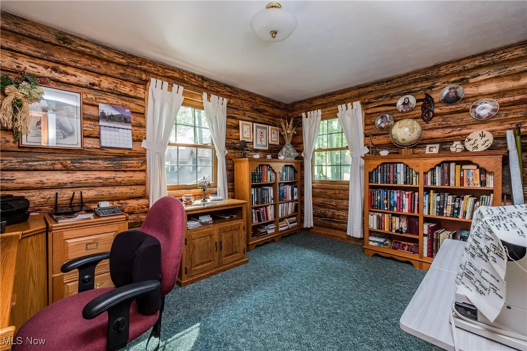 Office featuring rustic walls and dark carpet