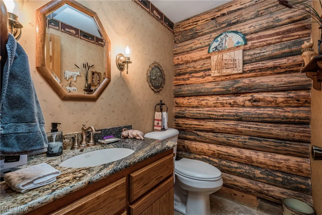 Half bath featuring rustic walls, vanity, and toilet