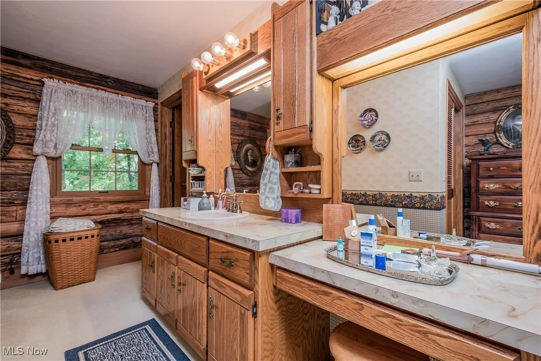 Full bath featuring wallpapered walls, rustic walls, and vanity