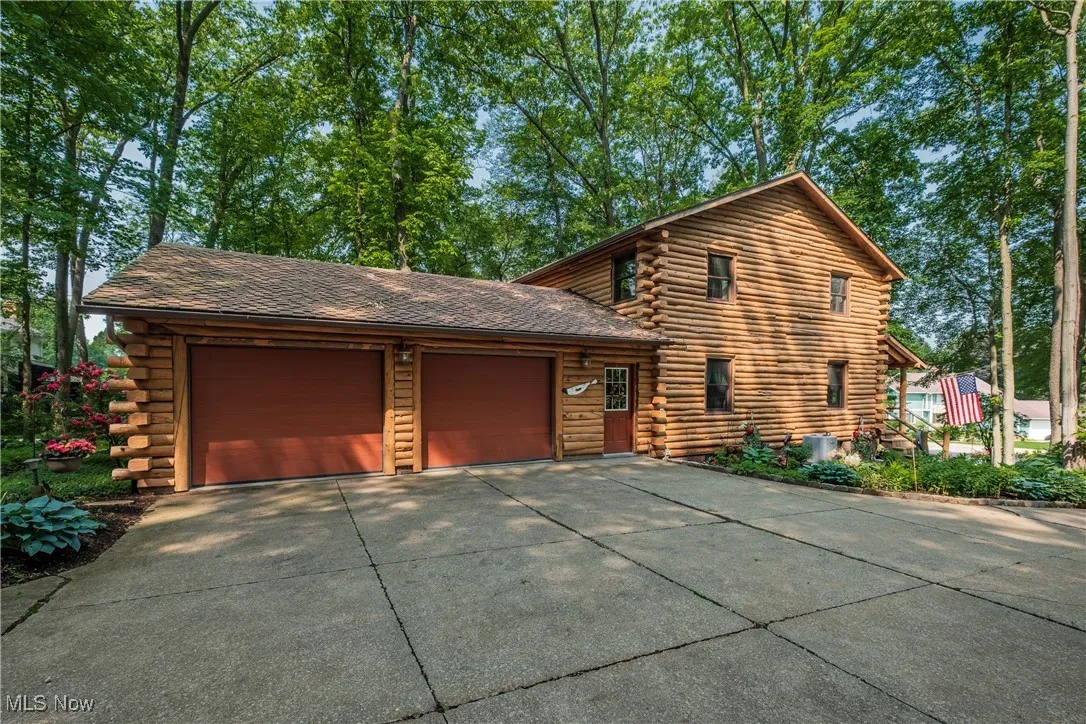 View of front of property with log exterior, concrete driveway, a garage, and central air condition unit