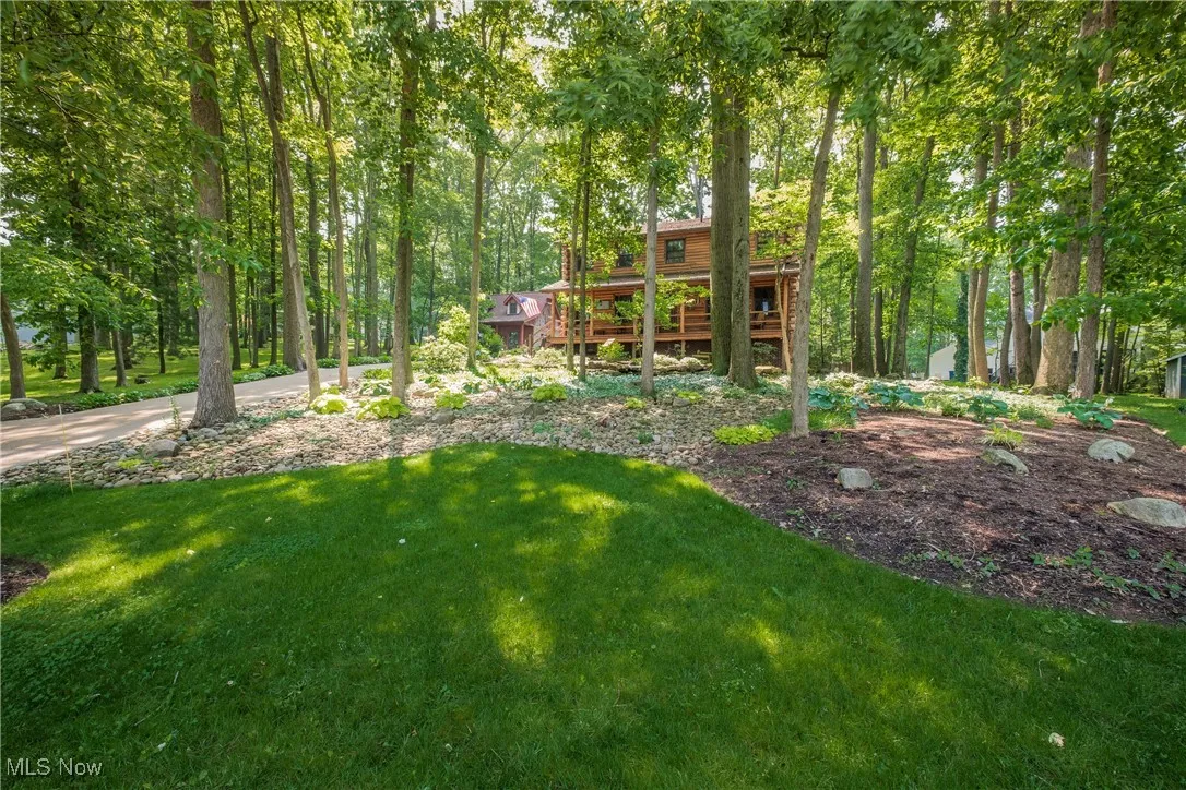 View of green lawn featuring a deck and a view of trees