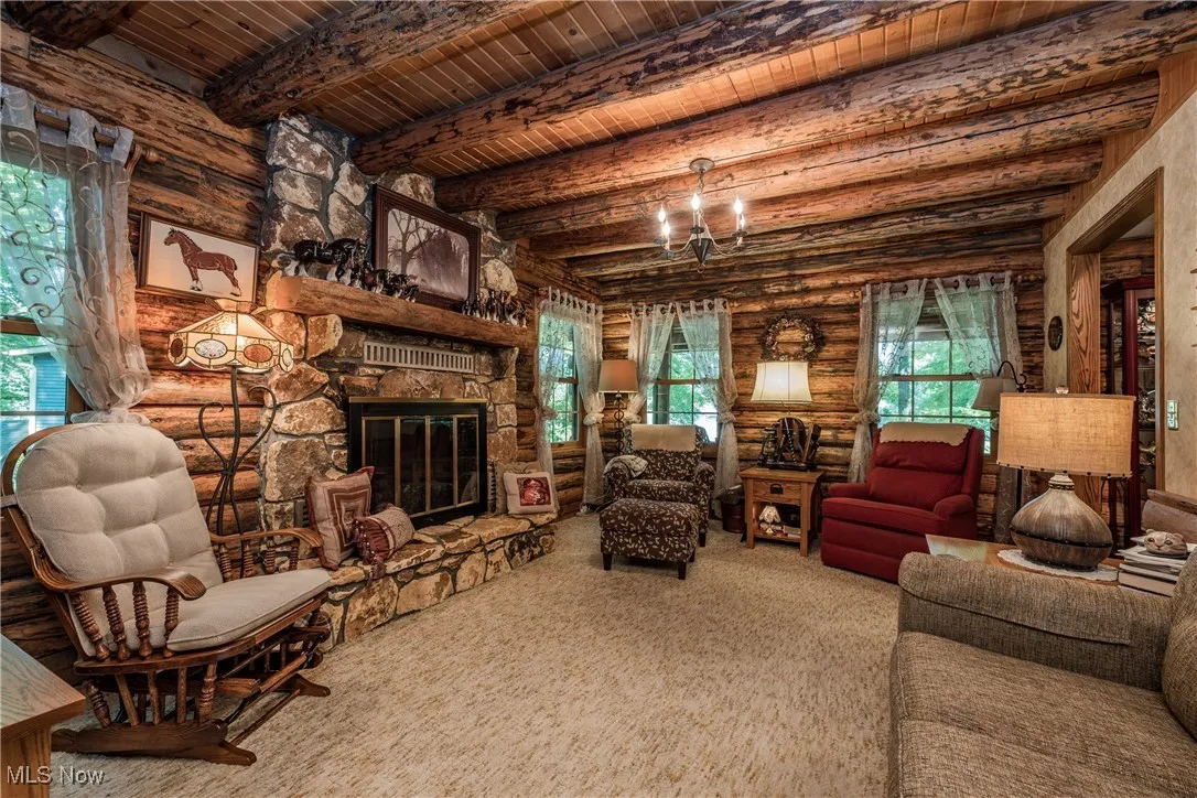 Carpeted living room featuring wooden ceiling with exposed beams and a fireplace