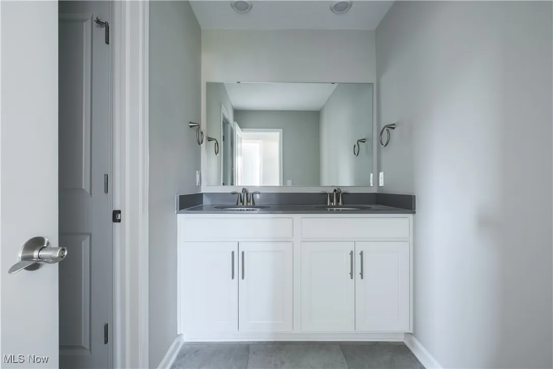 Full bath featuring double vanity and baseboards