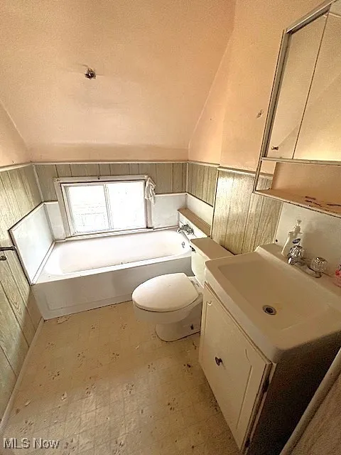 Full bathroom with tile patterned floors, a bath, vanity, and lofted ceiling
