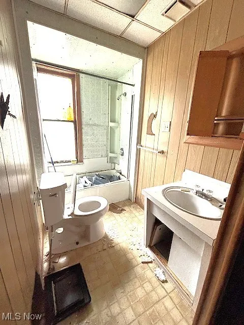 Full bathroom featuring wood walls, tub / shower combination, tile patterned floors, a drop ceiling, and vanity