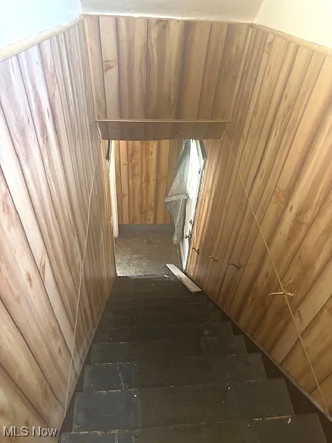 Staircase featuring wood walls