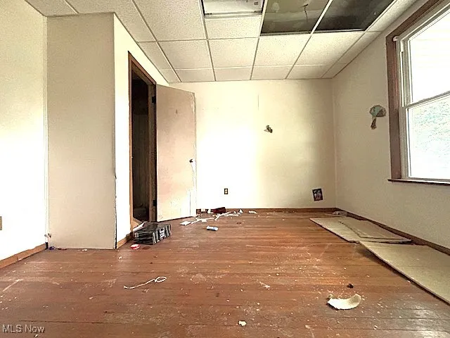 Unfurnished room featuring wood-type flooring and a drop ceiling