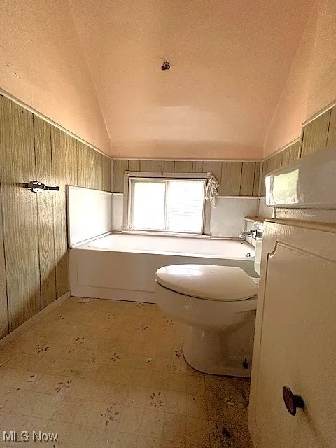 Bathroom with tile patterned floors, lofted ceiling, and a bath