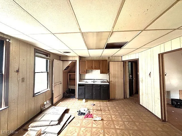 Kitchen with wood walls, light flooring, light countertops, and a drop ceiling