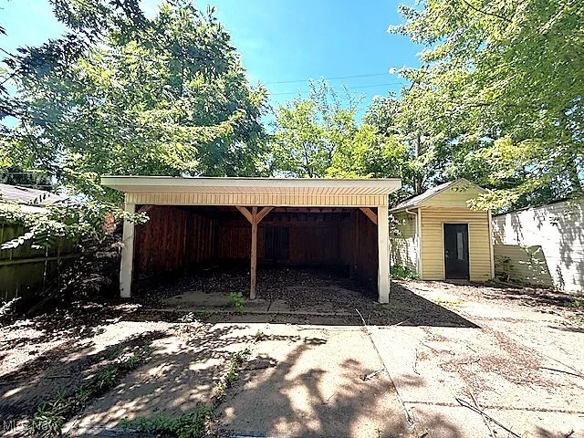 Garage with a carport, a shed, and concrete driveway