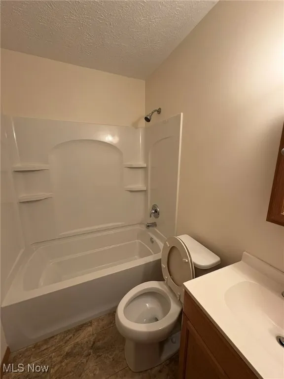 Full bathroom with a textured ceiling, shower / washtub combination, and vanity