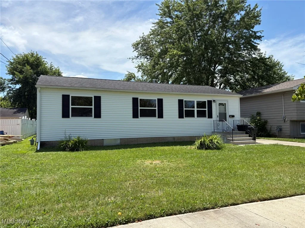 View of front facade with a front lawn, roof with shingles, and crawl space