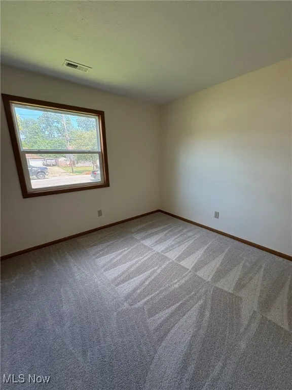Carpeted spare room featuring baseboards