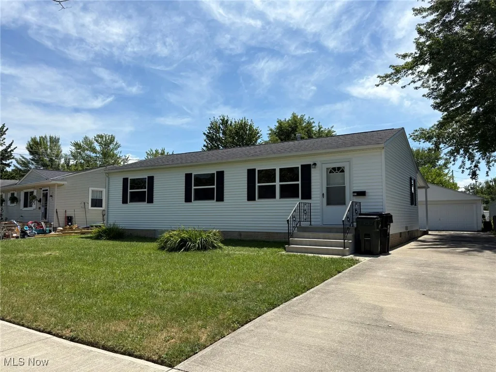 View of front of house with crawl space, an outdoor structure, a front yard, a detached garage, and entry steps