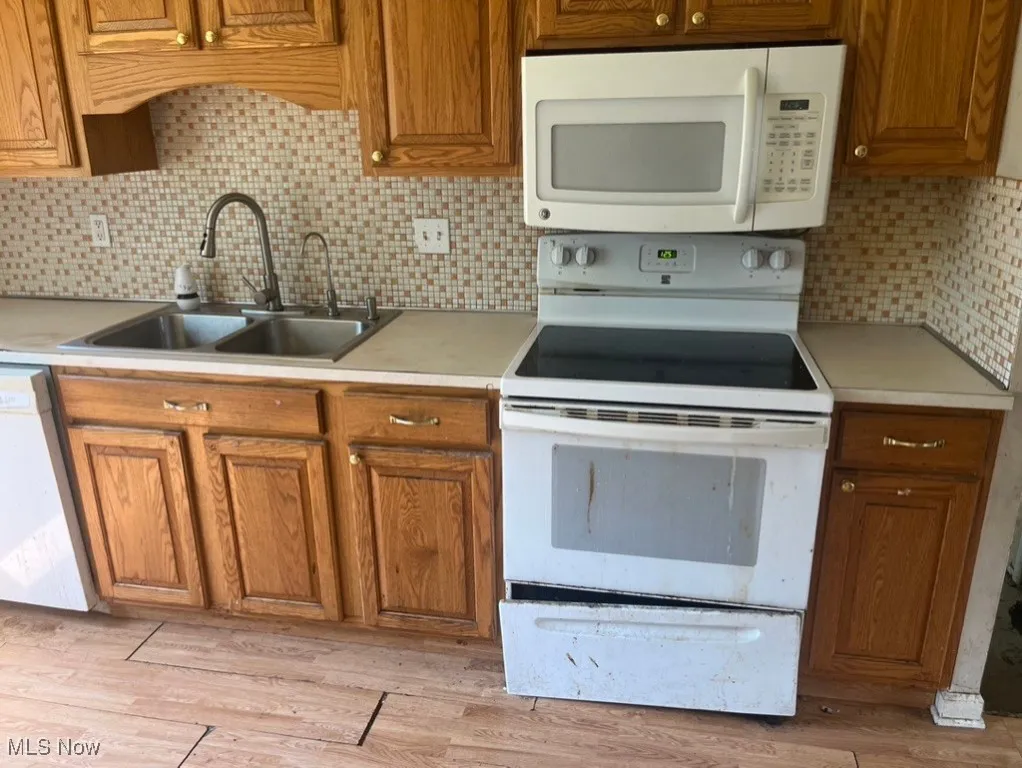 Kitchen featuring white appliances, light countertops, and brown cabinets