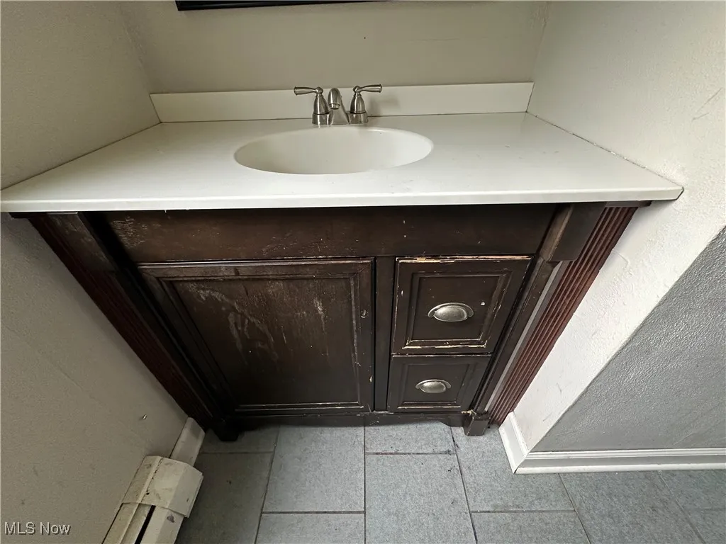 Bathroom with vanity, a textured wall, and tile patterned flooring