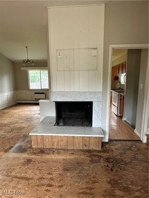 Detailed view of a multi sided fireplace, wood finished floors, a chandelier, and range