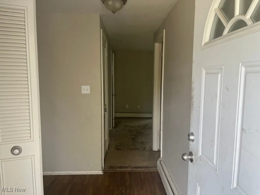 Corridor with baseboard heating and dark wood finished floors